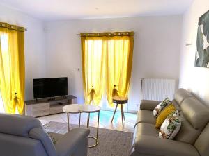 a living room with a couch and a tv and yellow curtains at Grace in Douzy