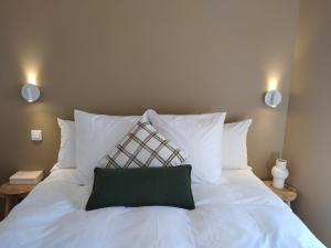 a white bed with a green pillow on it at Maison La Petite Cour - Spa in Visan