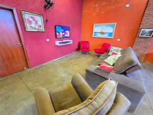 a living room with a couch and two red chairs at EcoNicolla Iguaçu Club House in Foz do Iguaçu
