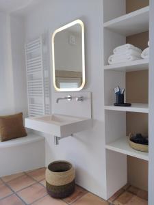 a white bathroom with a sink and a mirror at Maison La Petite Cour - Spa in Visan