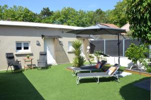 un patio con 2 sillas, una sombrilla y una mesa en Maison Bon Air Capbreton, en Capbreton