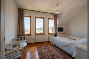 a bedroom with a bed and a desk and windows at Casa Cranta in Braşov