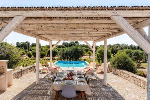 eine hölzerne Pergola mit Tischen und Stühlen und einem Pool in der Unterkunft Casa Sordella in San Michele Salentino