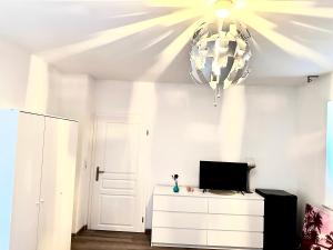 a living room with a television and a chandelier at Pension Jasmin B in Chemnitz