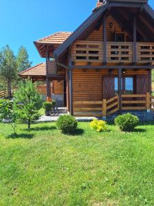 a log cabin with a grass yard in front of it at Vila Vodice Zlatibor in Vodice