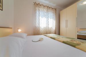 - une chambre avec un lit blanc et une fenêtre dans l'établissement Apartments Miamare, à Seget Vranjica