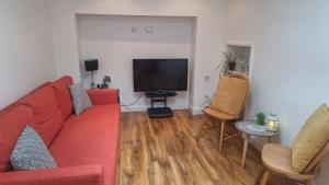 a living room with a red couch and a flat screen tv at Ballycastle Town Centre Apartment in Ballycastle