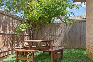 a picnic table and two benches in front of a fence at Near Texas A&M, Spacious Living Room, 4 Queen Beds in College Station