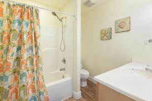 a bathroom with a shower curtain and a toilet at Tequila Mockingbird in Nags Head +54 photos