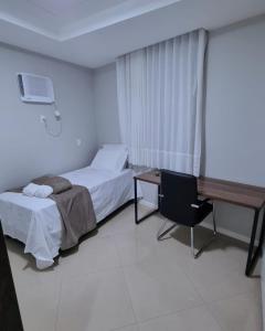 a hotel room with a bed and a desk and a desk at RefugioBacutia- Prédio FRENTE MAR Bacutia- 6 pessoas- 3 Quartos com AR sendo 1 suite - varanda- sala de estar e jantar Ampla -Piscina e Sauna no Prédio in Guarapari