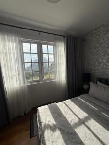 a bedroom with a bed and a large window at Villa Dhūmragiri in Maskeliya