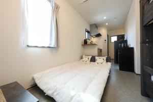 ein großes weißes Bett in einem Zimmer mit Fenster in der Unterkunft Drive & Sauna Stay 名古屋大曽根の宿 by NOAH HOTELS in Daikōchō