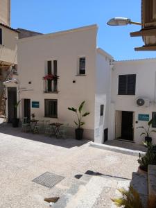 a white building with tables and chairs in a courtyard at Amuri Holiday Home in Agrigento