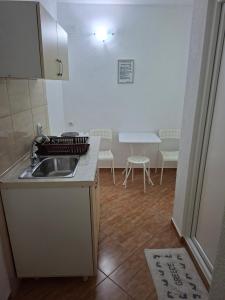 a kitchen with a sink and a table with chairs at Apartmani Milica Dojran in Star Dojran +12 photos