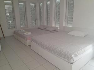 two beds in a white room with windows at Vila Magdalena-Star Dojran in Star Dojran
