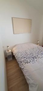 a bedroom with a bed and a nightstand next to it at Charmante maison de plain pied rénovée et climatisée en lisière de forêt in Saint-Jean-de-Monts
