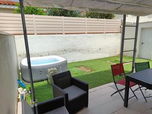 a hot tub on a patio with a table and chairs at Maison spacieuse agréable in Perpignan