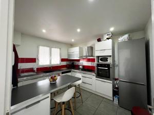 a kitchen with white cabinets and red accents at Maison spacieuse agréable in Perpignan