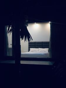 a bed in a dark room with a palm tree at Mountain river farm resort in Agali +1 photo