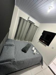 a bedroom with a bed and a flat screen tv at Hotel e Pousada Sao Miguel in Posse