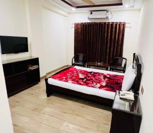 a bedroom with a bed with a red comforter and a television at Citymax Hotel in Rawalpindi