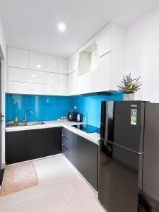 a kitchen with white cabinets and a black refrigerator at NhiNhi Homestay in Thôn Văn Dương