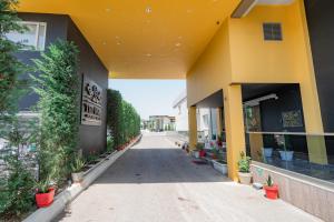 a yellow building with potted plants and a sidewalk at The One Boutique Hotel in Muçaj