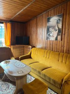 a living room with a yellow couch and a table at Anker Kotwica in Łeba
