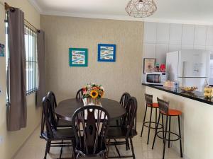 a kitchen with a table with chairs and a refrigerator at Vila Sunset Saquarema RJ in Saquarema
