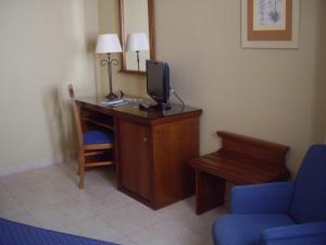 Pokój z biurkiem, telewizorem i niebieskim krzesłem w obiekcie Hotel Manolo Mayo w mieście Los Palacios y Villafranca