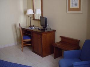 um quarto com uma secretária, uma televisão e uma cadeira azul em Hotel Manolo Mayo em Los Palacios y Villafranca
