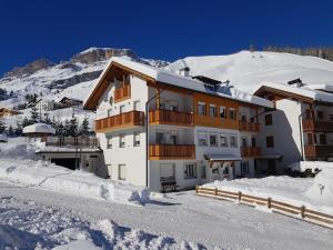 a building in the snow with a mountain in the background at Apartments Alpenroyal Arabba - Check-in at Garni Royal in Arabba
