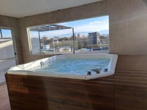 a large bath tub with a large window in a bathroom at Gran Hotel Dakar in Mendoza