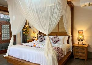 a bedroom with a canopy bed with white curtains at Maharatu Suite Villa in Ubud +57 photos
