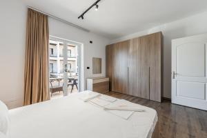 a bedroom with a white bed and a wooden cabinet at Saranda Beach Living - 1BR Apartment in Sarandë +28 photos