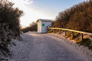 a small building on the side of a dirt road at Gemütliches Sylter Strandstudio in Sylt +5 photos