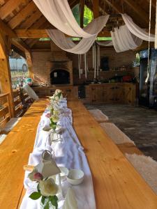 a long wooden table with dishes and flowers on it at Căsuța cu doi brazi in Baia Mare