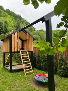 a play house with a ladder in a yard at Căsuța cu doi brazi in Baia Mare