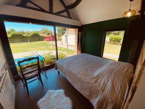 une chambre avec un lit et une grande fenêtre dans l'établissement Les Volets Bleus, à Cormont