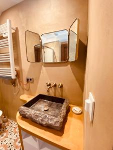 une salle de bain avec un lavabo en pierre et un miroir dans l'établissement Les Volets Bleus, à Cormont