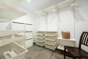 a walk in closet with white cabinets and a wooden chair at "Sun down" by Corralejobeach Apartments in Corralejo