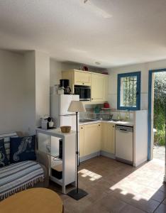 a kitchen with white cabinets and a couch in a room at MAZET - Domaine de la Pinède PRAMOUSQUIER - Le Lavandou in Le Lavandou