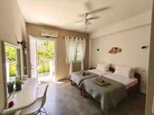 a bedroom with two beds and a table and a window at New Poseidon Apartments & Studios in Skala Eresou