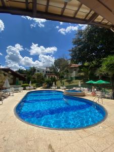 a large blue swimming pool with chairs and umbrellas at Hotel Fazenda Tucano in Capim Branco