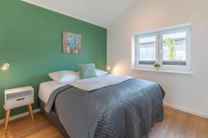 a bedroom with a bed and a green wall at Huus Blaumees in Kating