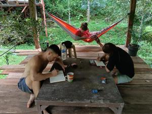 a group of people sitting around a table in a hammock at Devalley Basecamp in Kampong Ulu Dong