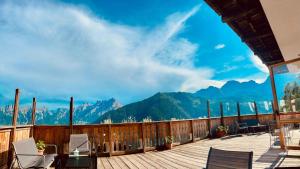 a deck with chairs and a view of mountains at HG Hotel La Caminatha in Val di Zoldo