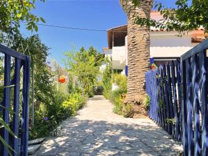 a blue fence next to a tree and a sidewalk at New Poseidon Apartments & Studios in Skala Eresou