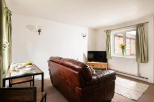 a living room with a leather couch and a table at Swingletree Cottage in Bridlington