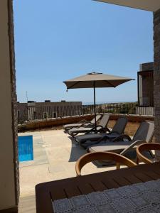 a row of lounge chairs and an umbrella on a roof at Turquoise Pool Side Thymus Resort in Himare